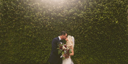 bride and groom by ivory wall