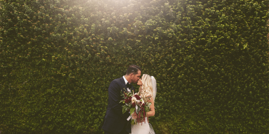 bride and groom by ivory wall