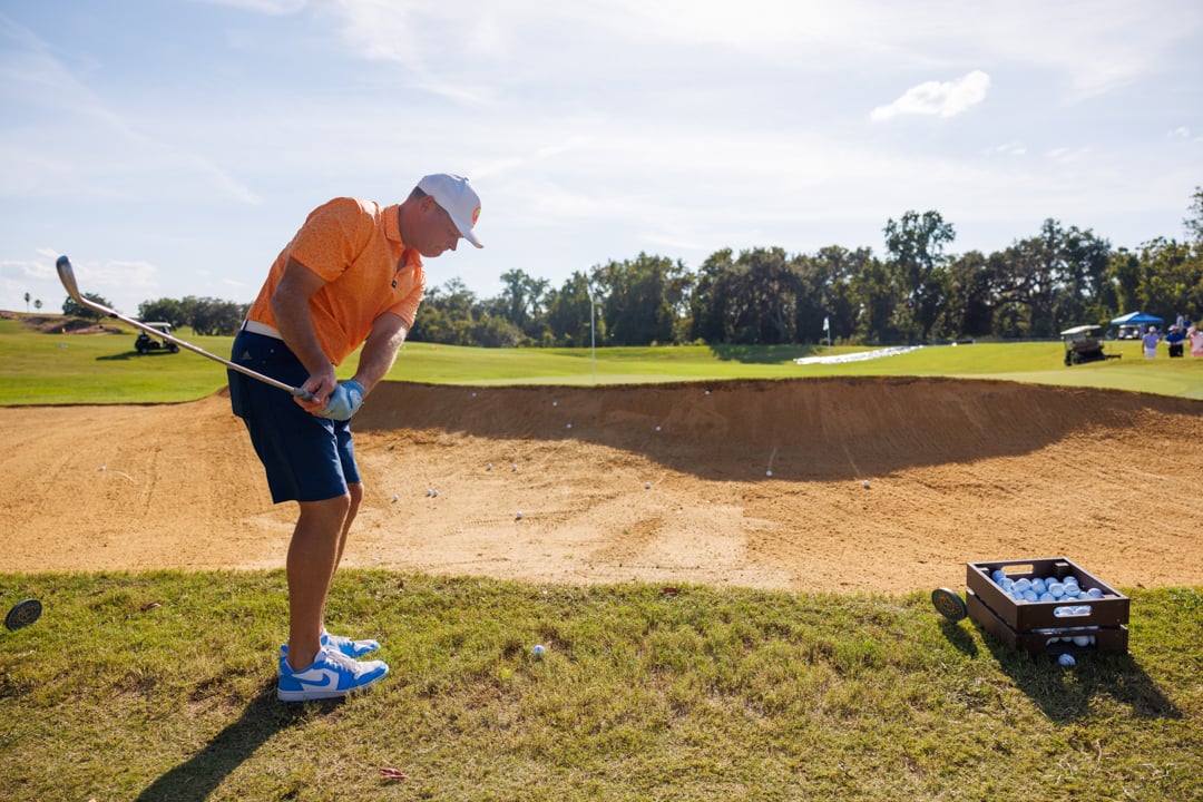 Man hitting over bunker to green at Bella Collina golf course