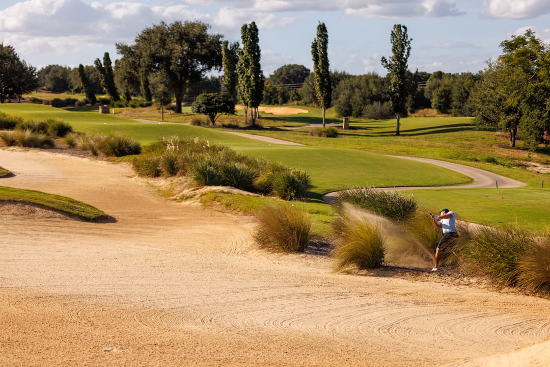Man taking a bunker shot at Bella Collina golf course