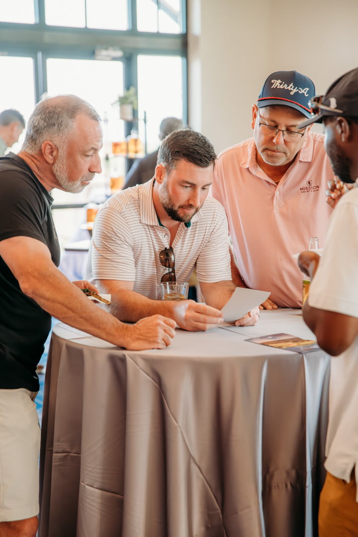 Group of men at table viewing a card