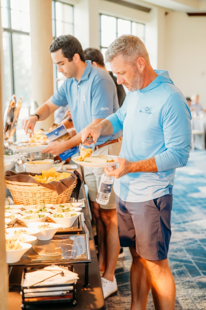 Men going through a food buffet at Bella Collina event