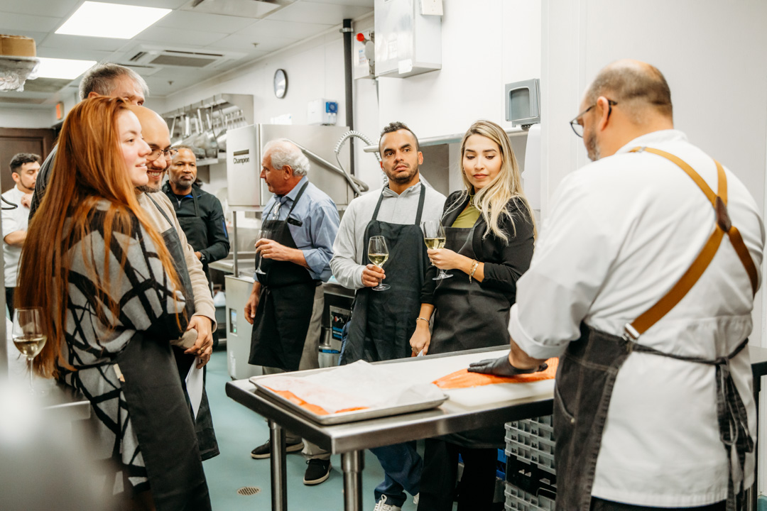 Group watching chef trim fish as Bella Collina event