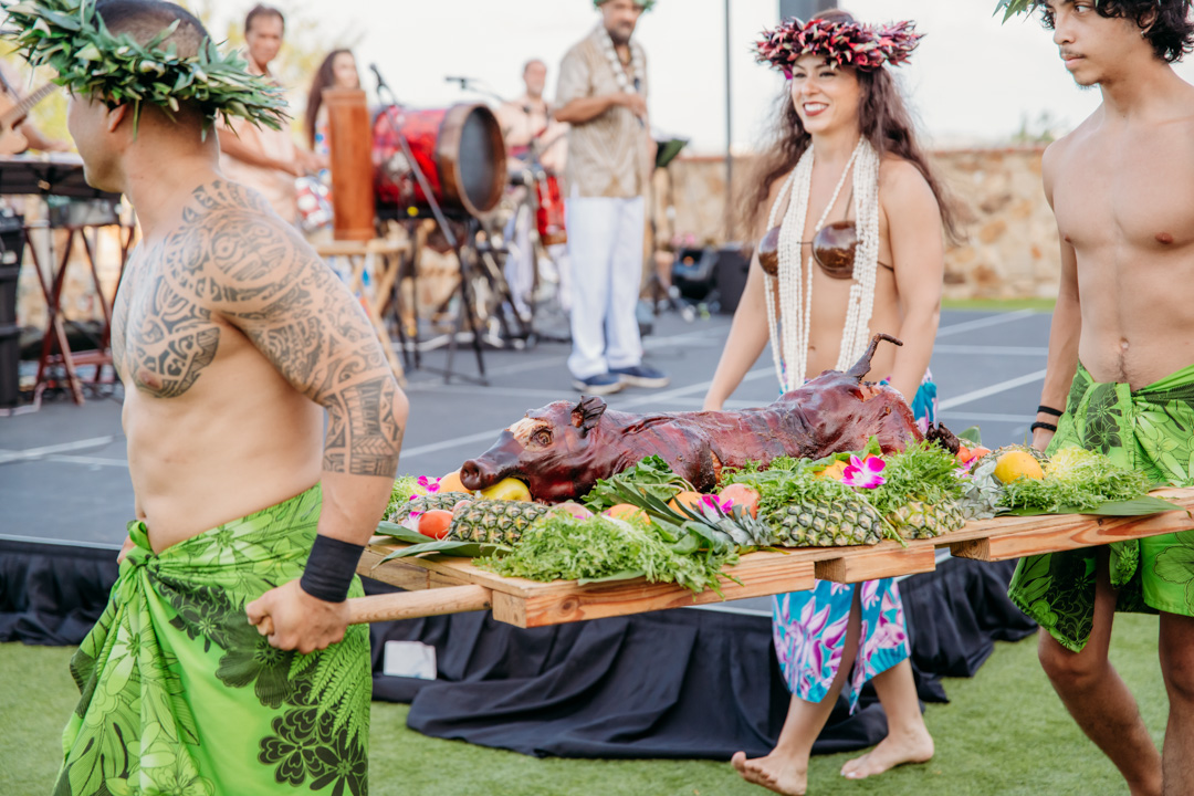 Men carrying roasted pig at Bella Collina event