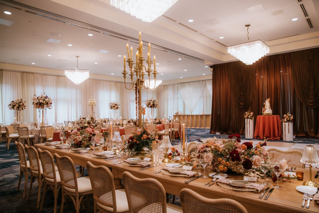 Ballroom dining tables with floral centerpieces and gold candelabras at Bella Collina
