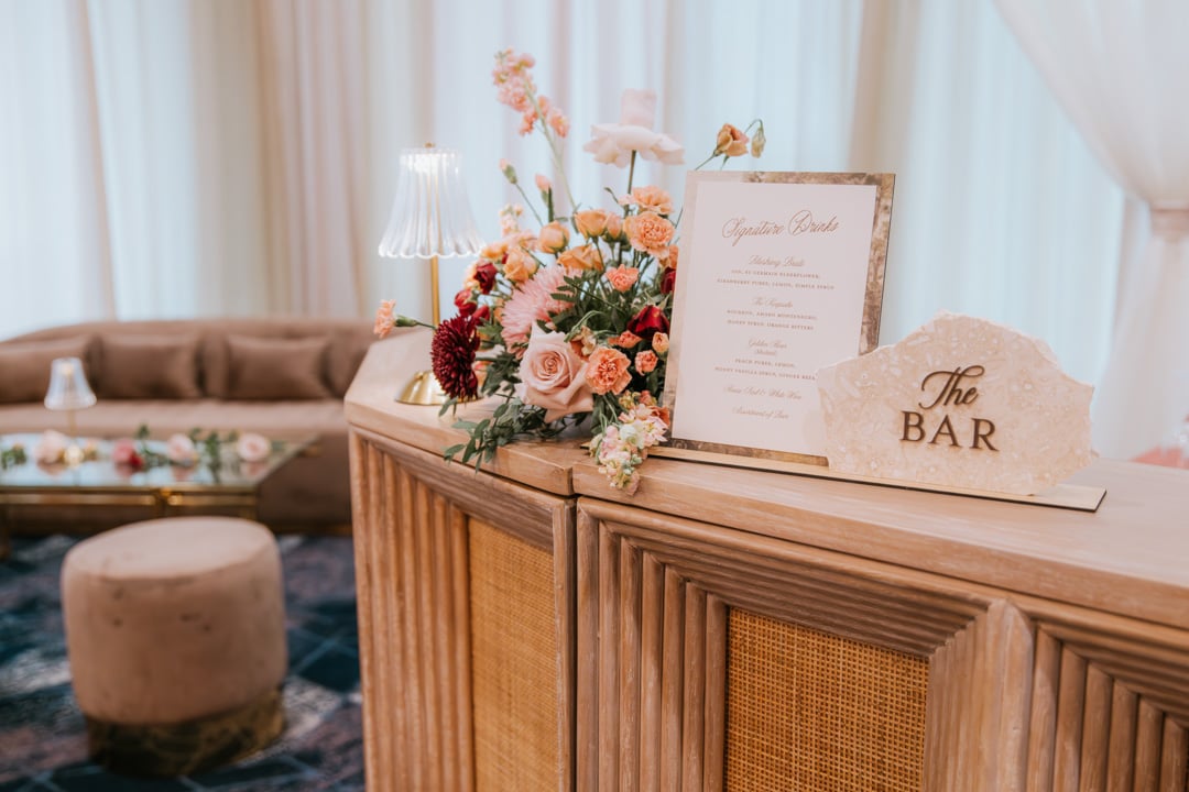 Custom bar display with floral arrangement and signature drink menu at Bella Collina
