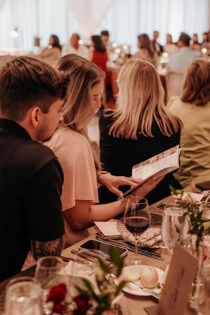 Guests review menus while seated at an elegant dining table at Bella Collina wedding tasting event