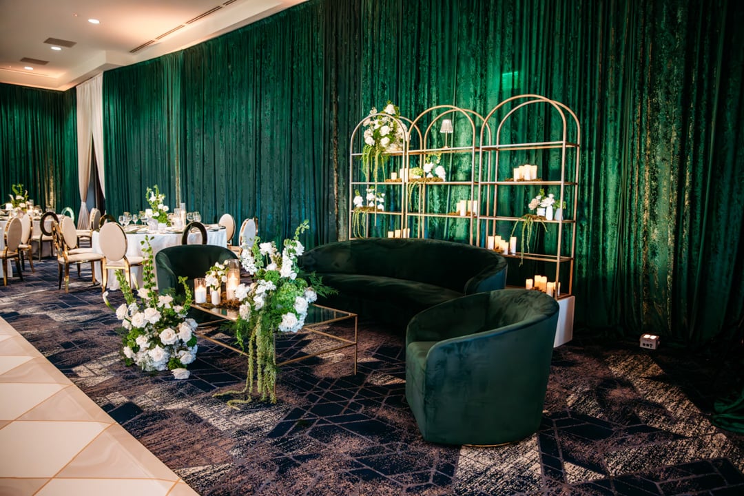 Elegant event space with green draping, lounge seating and floral décor at Bella Collina