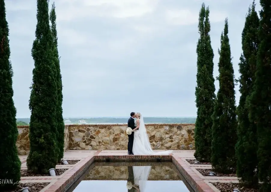 Bride and groom embracing beside the Reflection Pool at Bella Collina