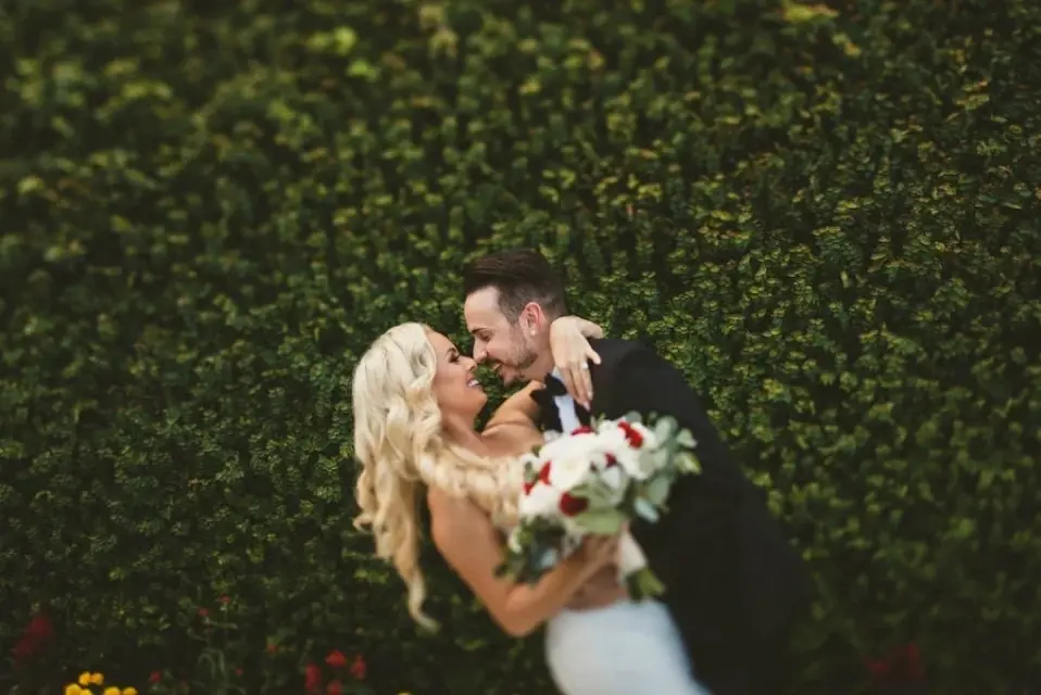Groom dipping and kissing his bride in the gardens at Bella Collina
