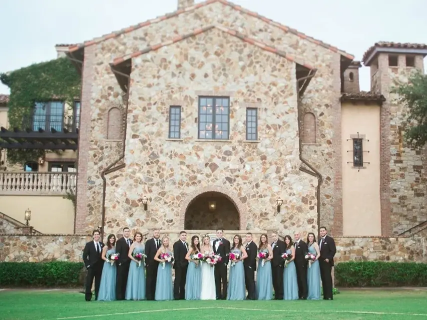 Wedding party posing in front of the stone Clubhouse at Bella Collina