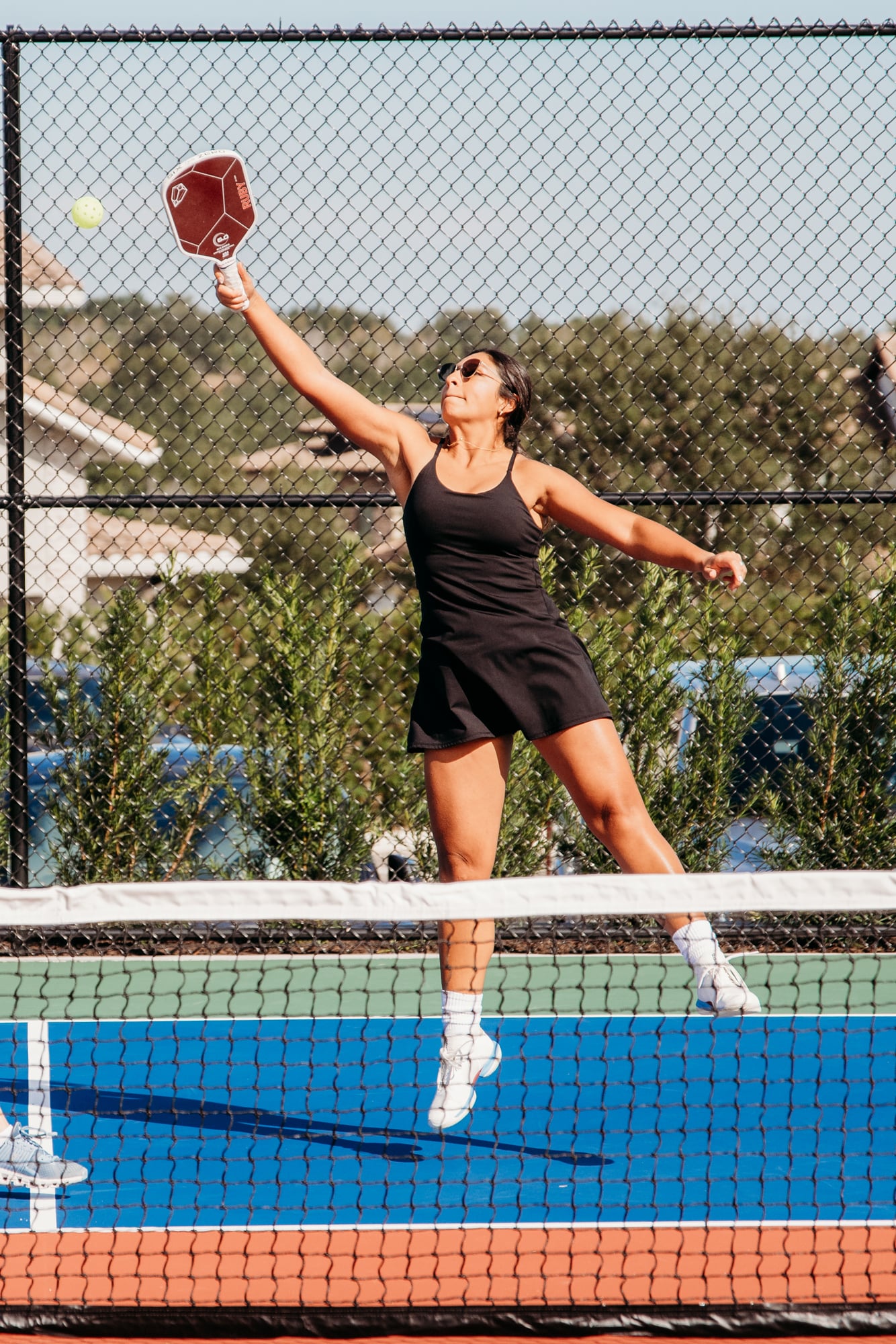 Woman jumping to hit ball while playing pickleball at Bella Collina