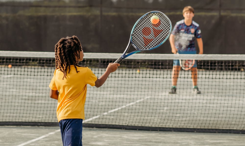 Child hitting forehand shot playing tennis at Bella Collina
