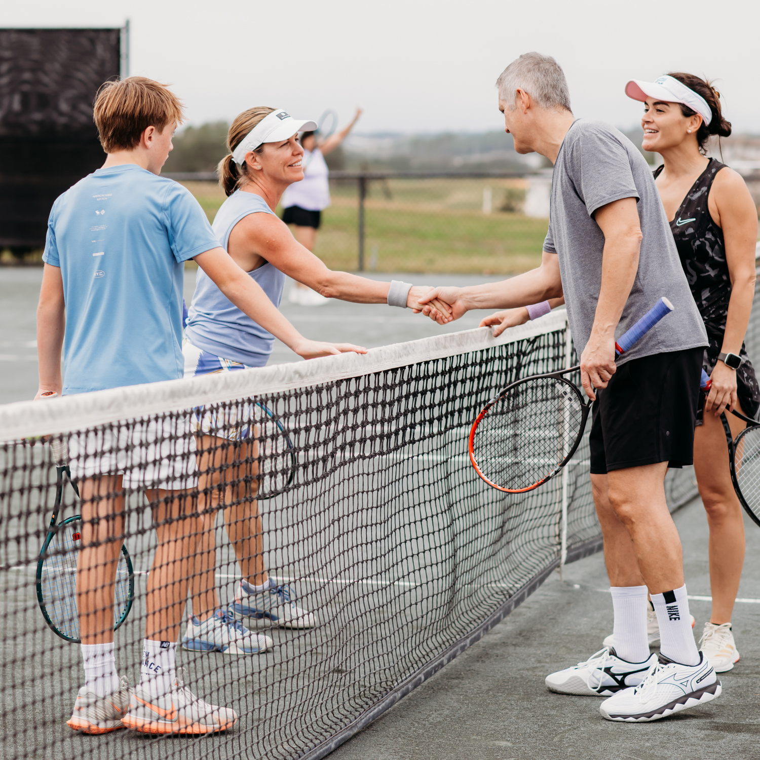Mixed doubles tennis players congratulating each other at the net at Bella Collina tennis courts