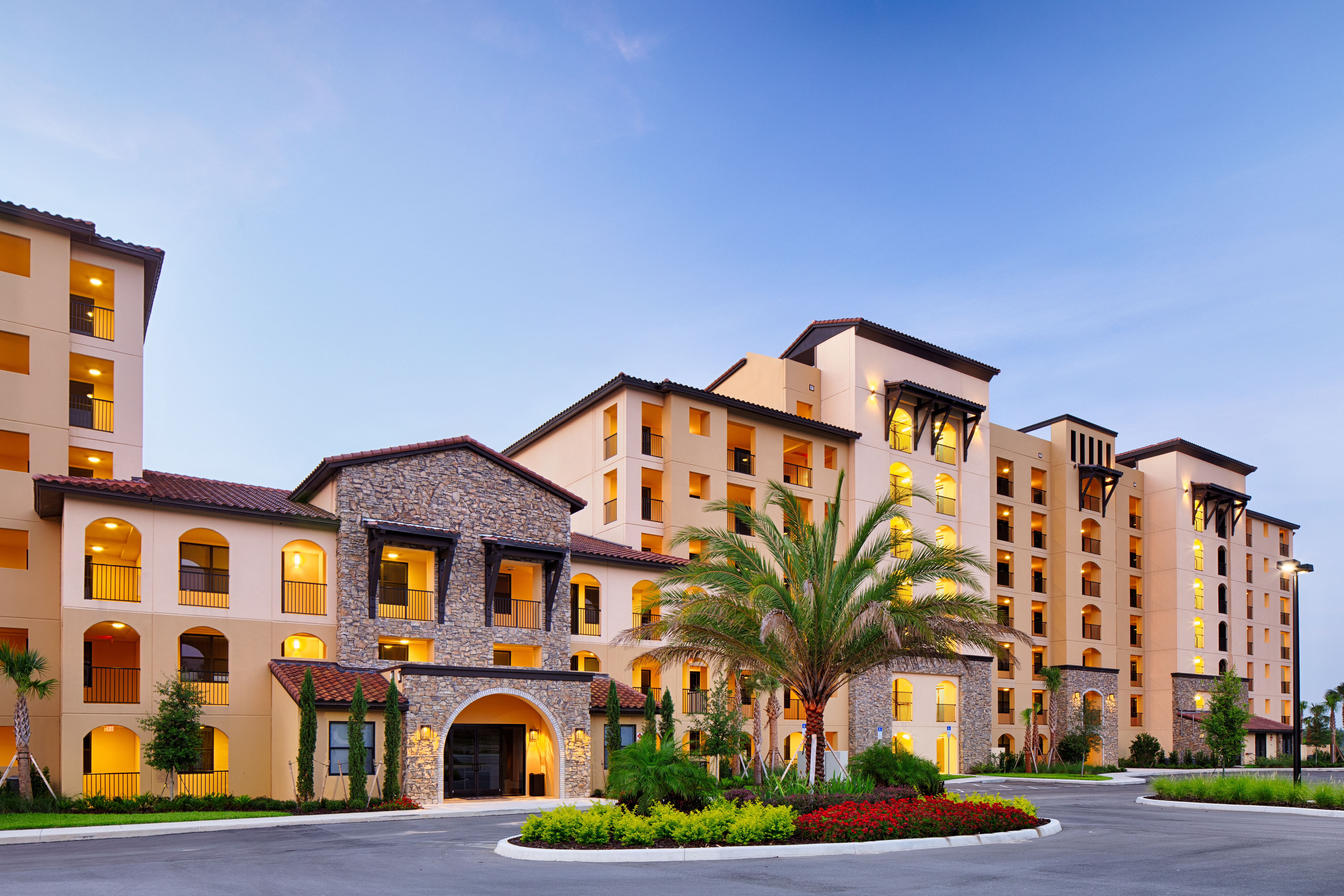Siena at Bella Collina condominium building with palm trees and landscaped entrance