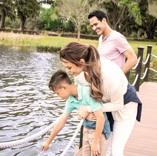 Couple and child standing on pier at lake