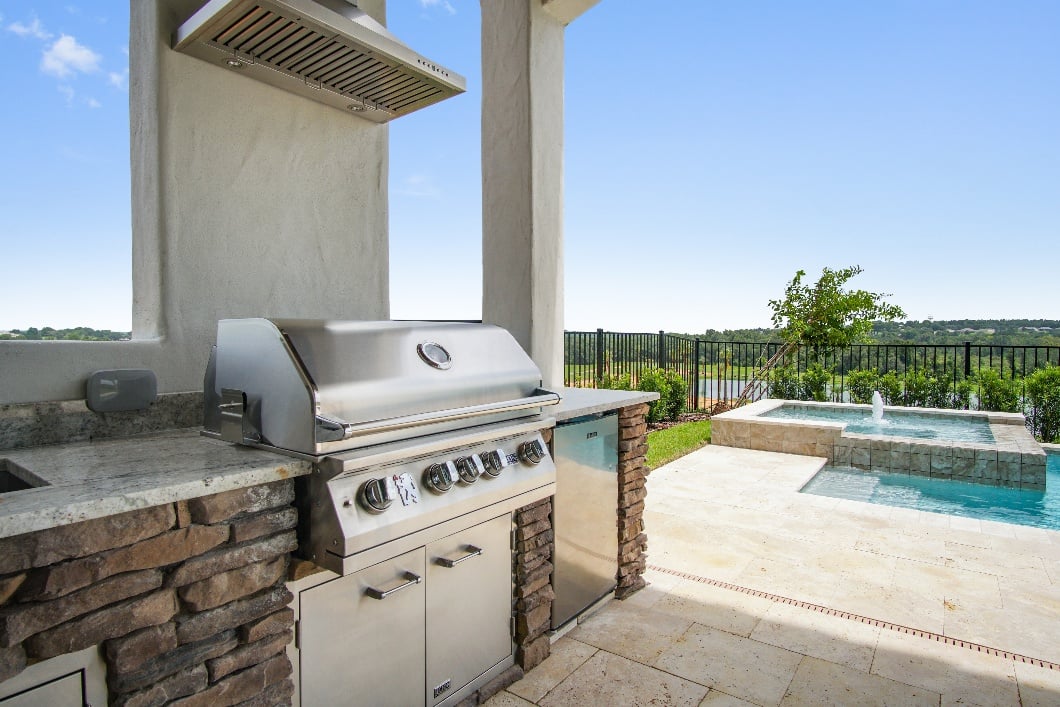 Covered outdoor kitchen with built-in grill overlooking the pool and spa at a Bella Collina home