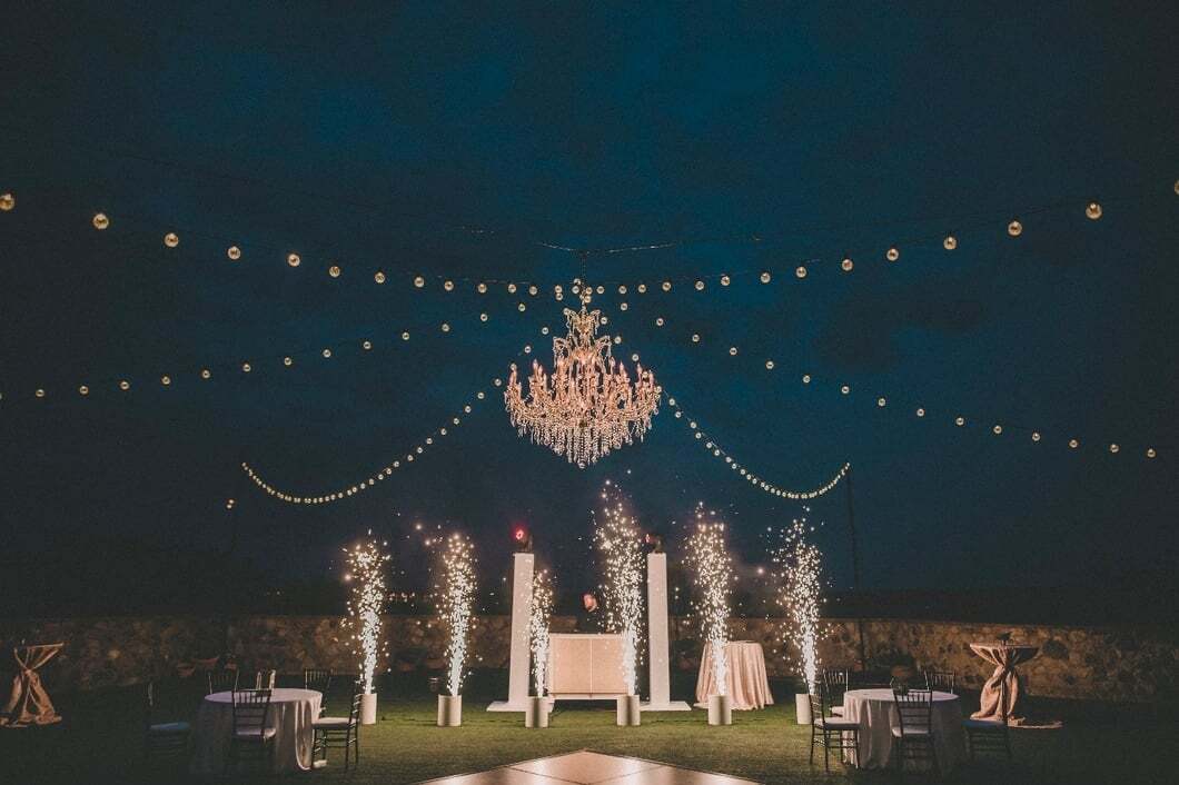 Evening Grand Lawn event with chandelier, string lights, and illuminated fountains at Bella Collina
