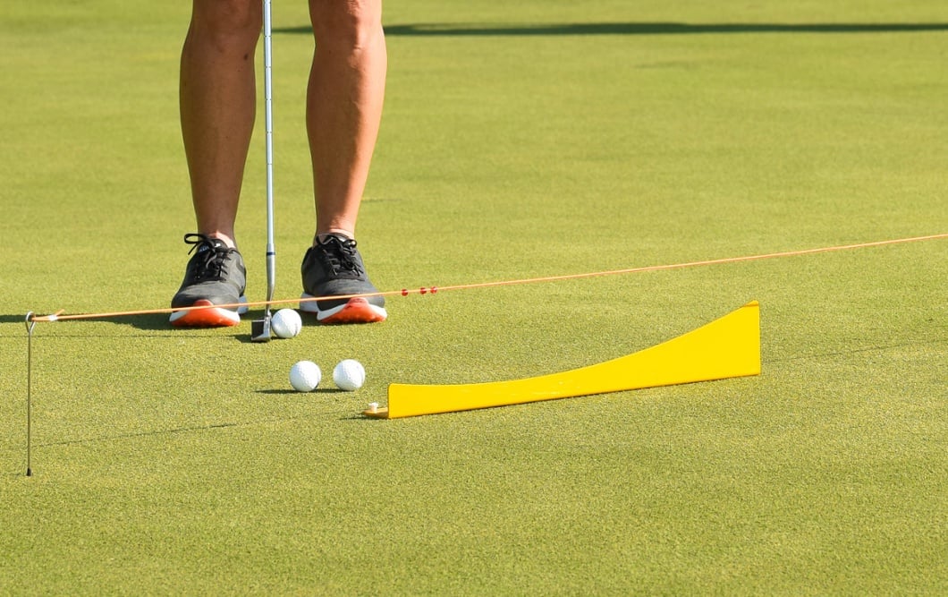 Student practicing putting with training aid