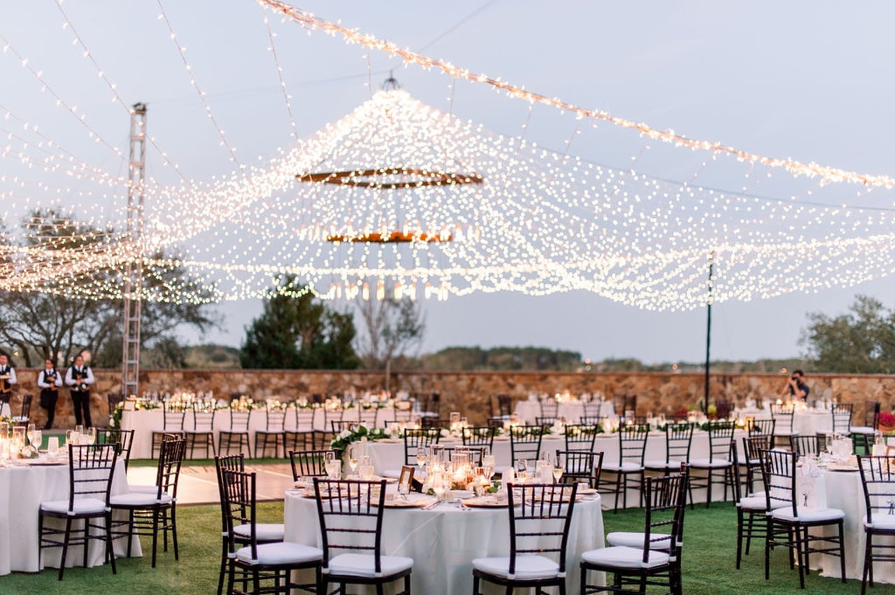 Grand Lawn event with dining tables beneath a canopy of string lights at Bella Collina
