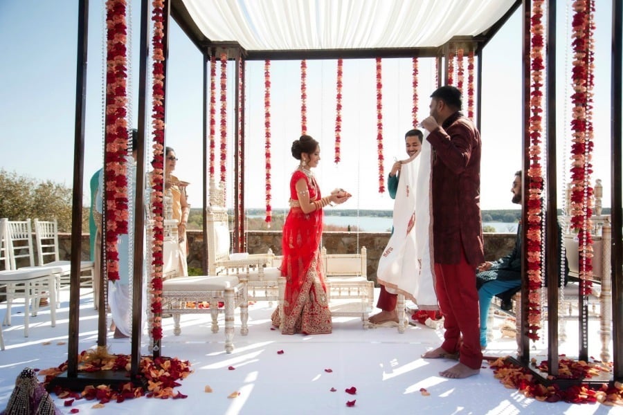 Couple exchanging vows beneath a colorful floral mandap at Bella Collina
