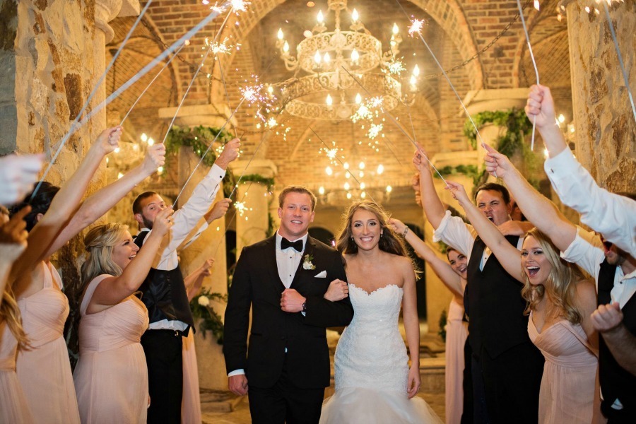Newlywed couple celebrating beneath sparklers in the Bella Collina atrium