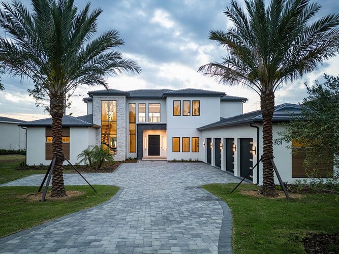 Luxury custom home with palm trees and paver driveway at Bella Collina