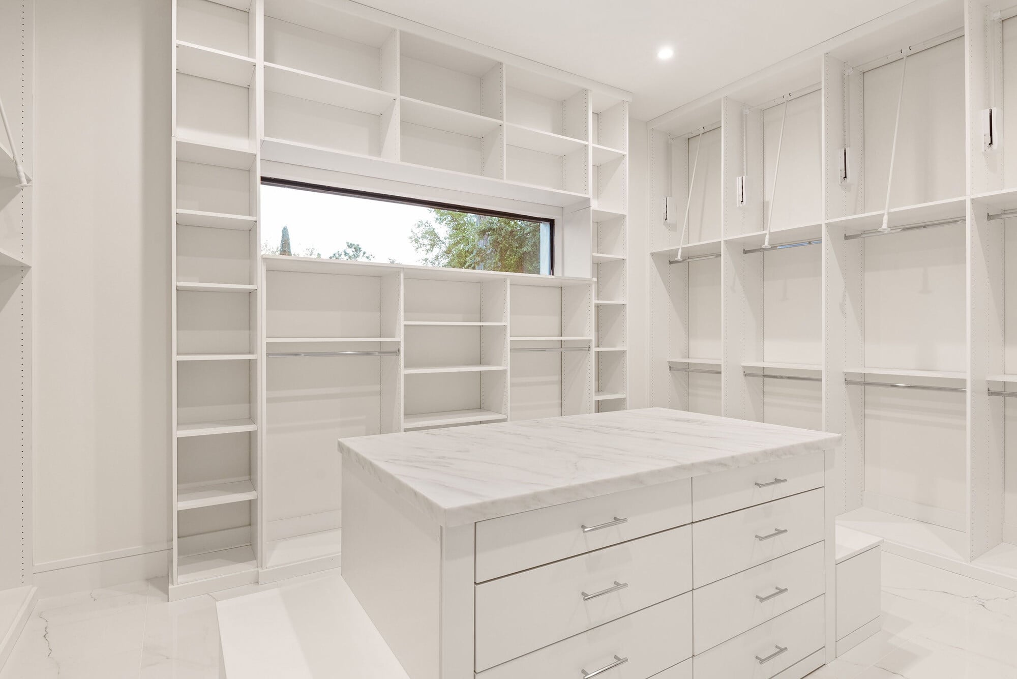 Luxury walk-in closet with custom white shelving and center storage island in a Bella Collina home