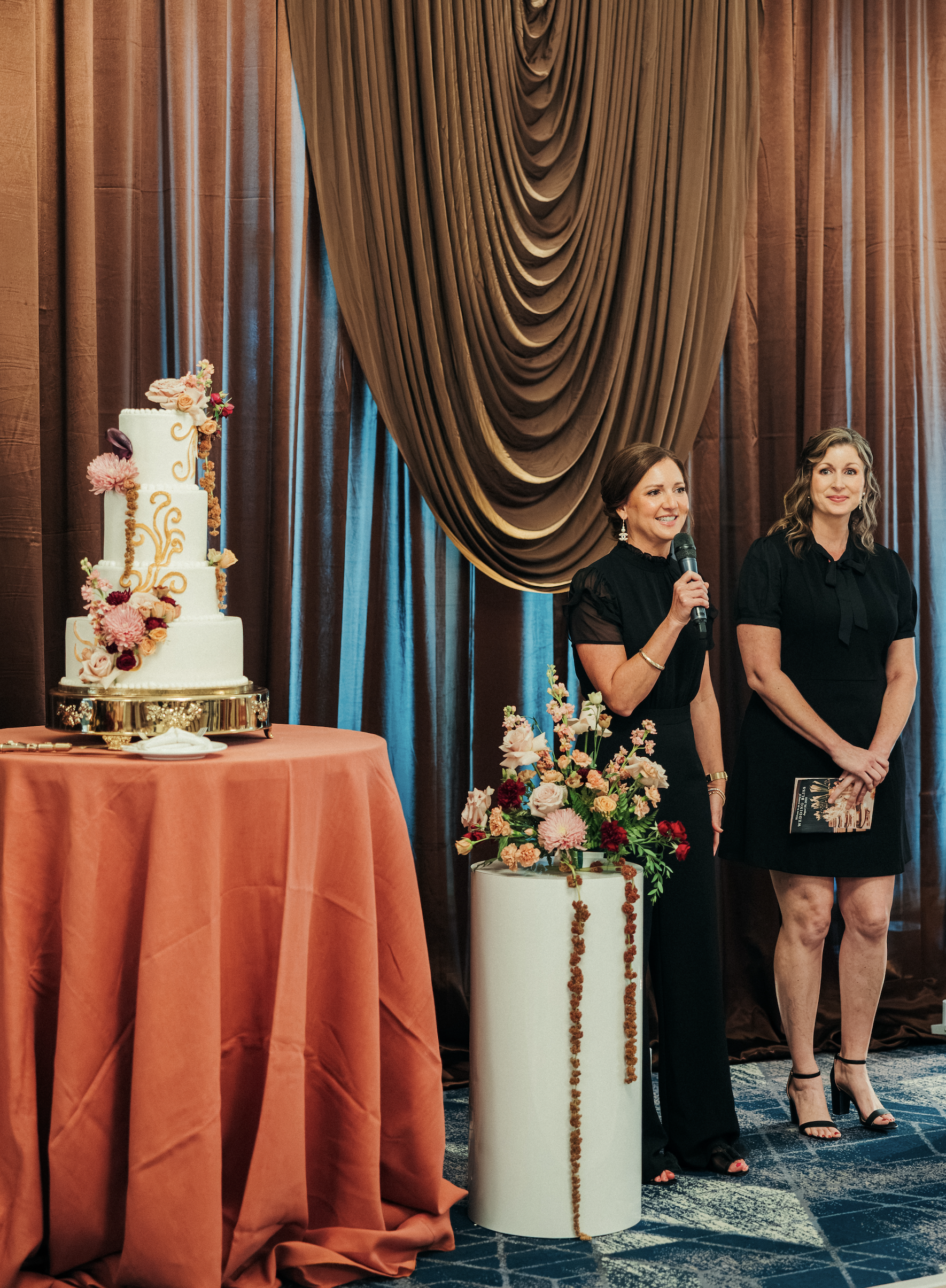Bella Collina staff presenting beside a wedding cake and floral display