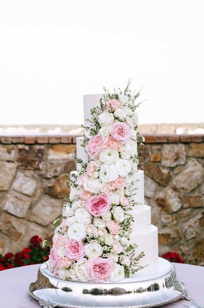 Tall white wedding cake covered with cascading pink and white flowers at Bella Collina