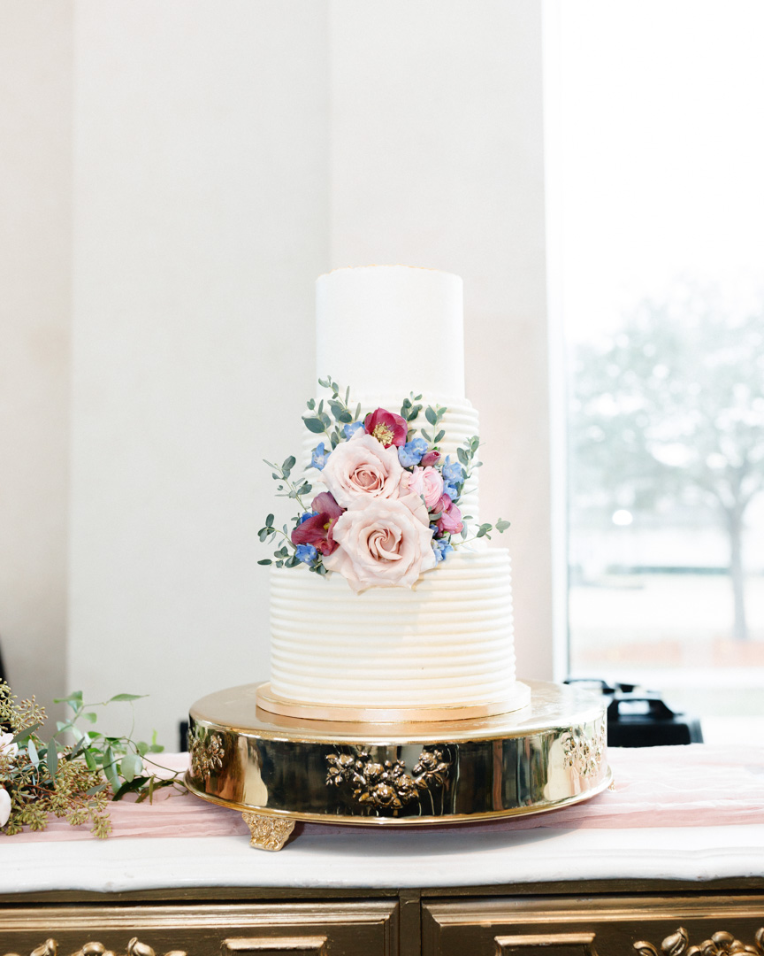 Three-tier white wedding cake with pink and white flowers at Bella Collina