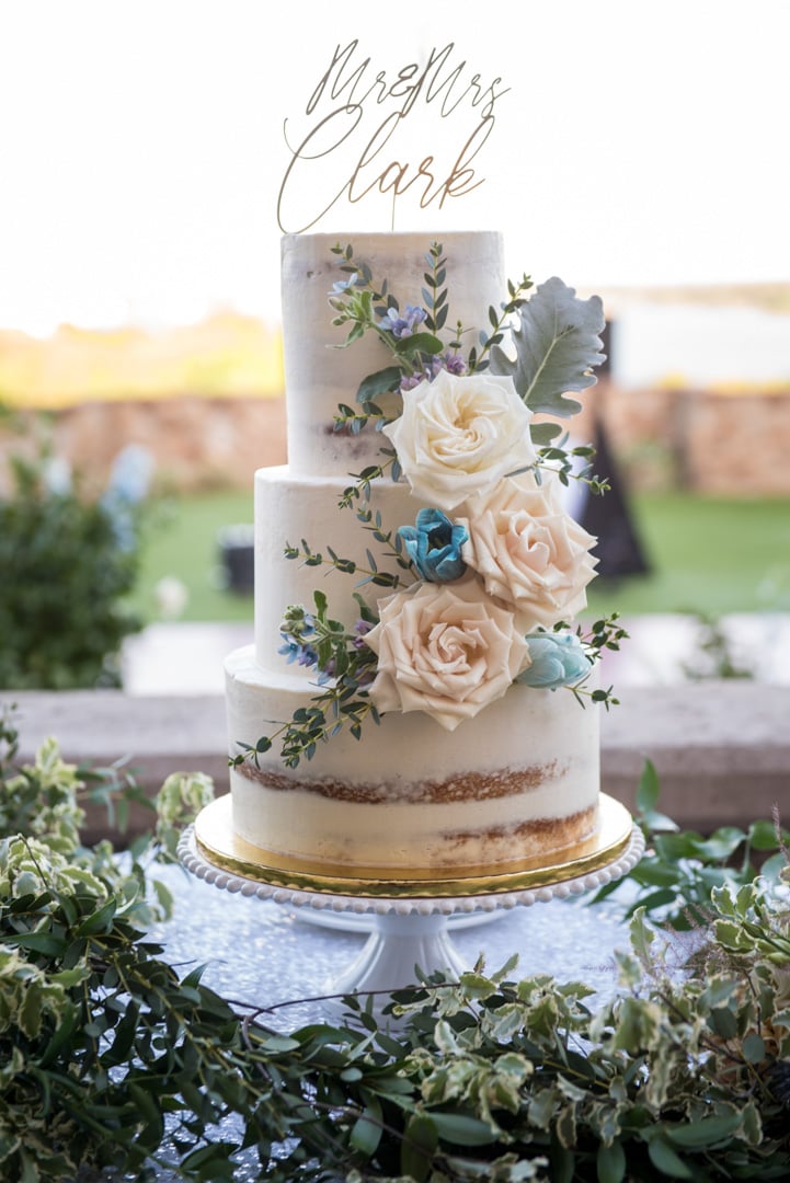 Three-tier white wedding cake with blush roses and greenery at Bella Collina