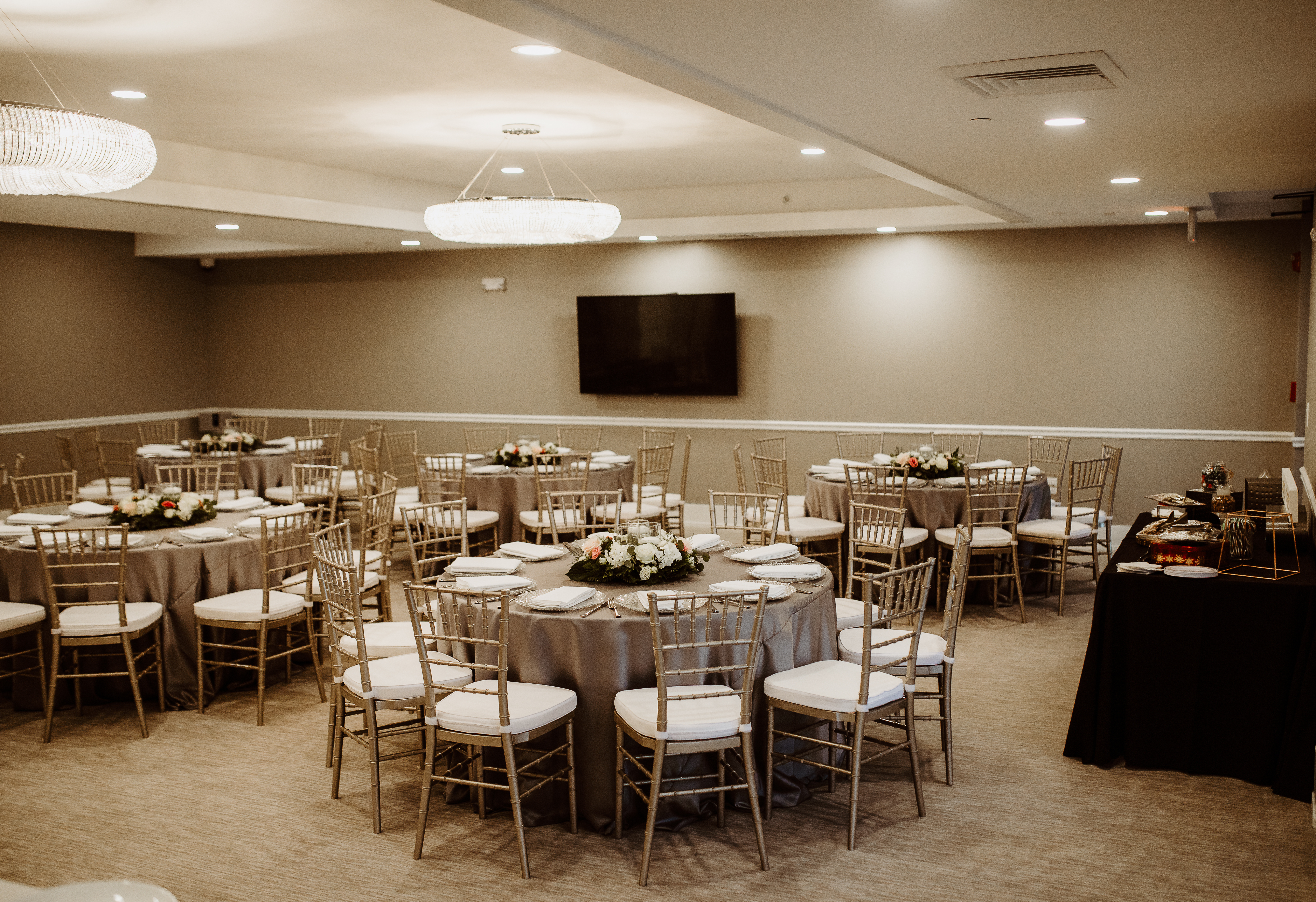 Wedding reception setup with round tables and gold chairs in the Siena Event Room at Bella Collina